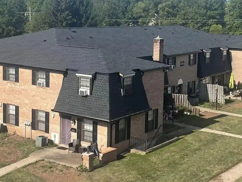Large residential building with new black shingles installed on its roof by Jim Miller Inc.